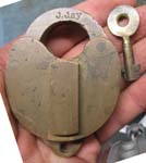 “J. JAY”. 3 1/4″ high. Brass body. Brass shackle. The reverse of the lock is bla